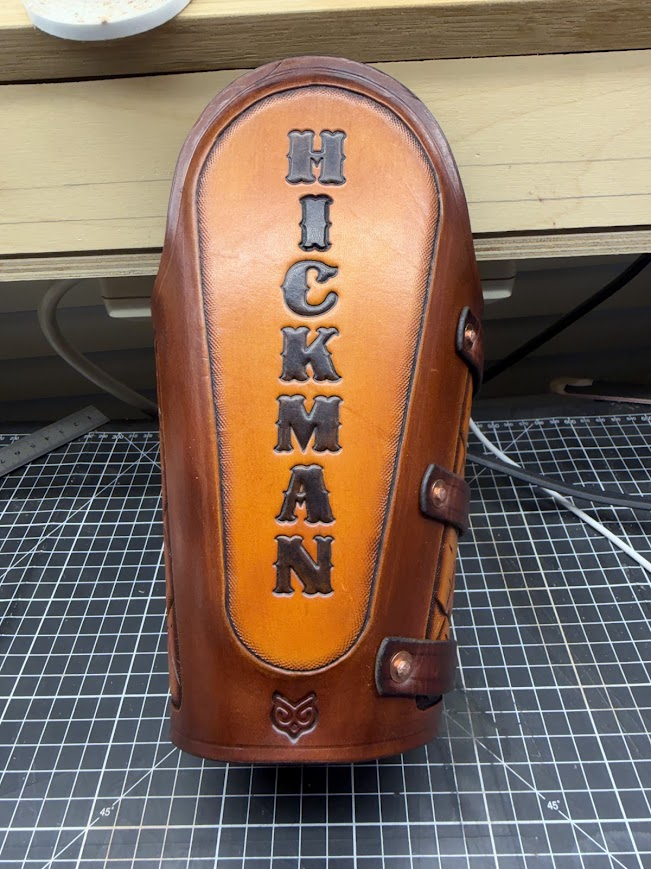 Custom leather welder's arm guard front view with HICKMAN name stamp and Barn Owl maker's mark